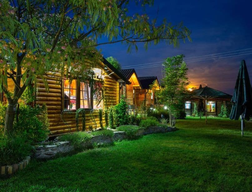 Drveni bungalovi na Camping Sosul u vreme zalaska sunca sa toplim svetlom i okolinom